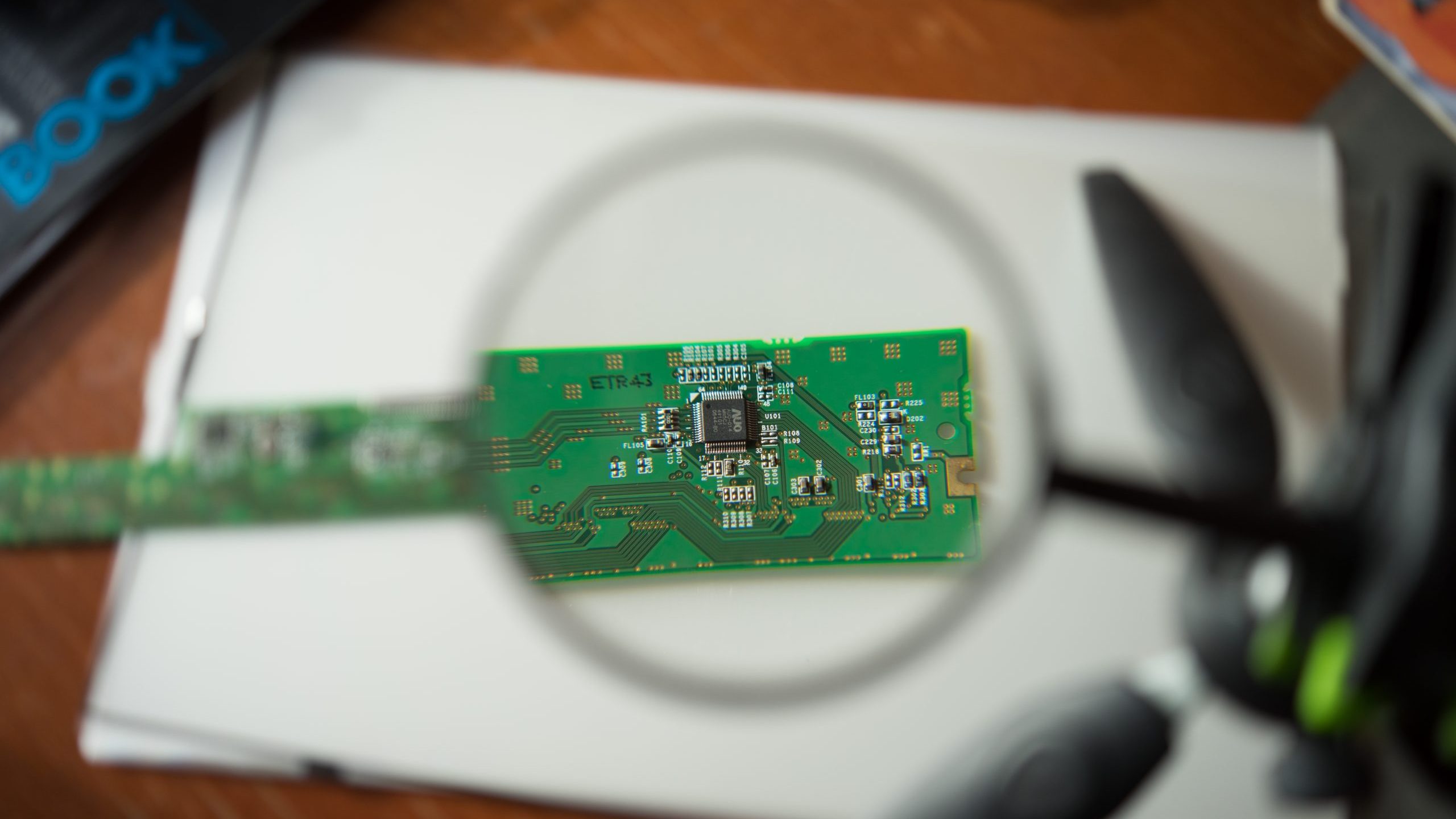 Engineer looking at a circuit board through a magnifying glass